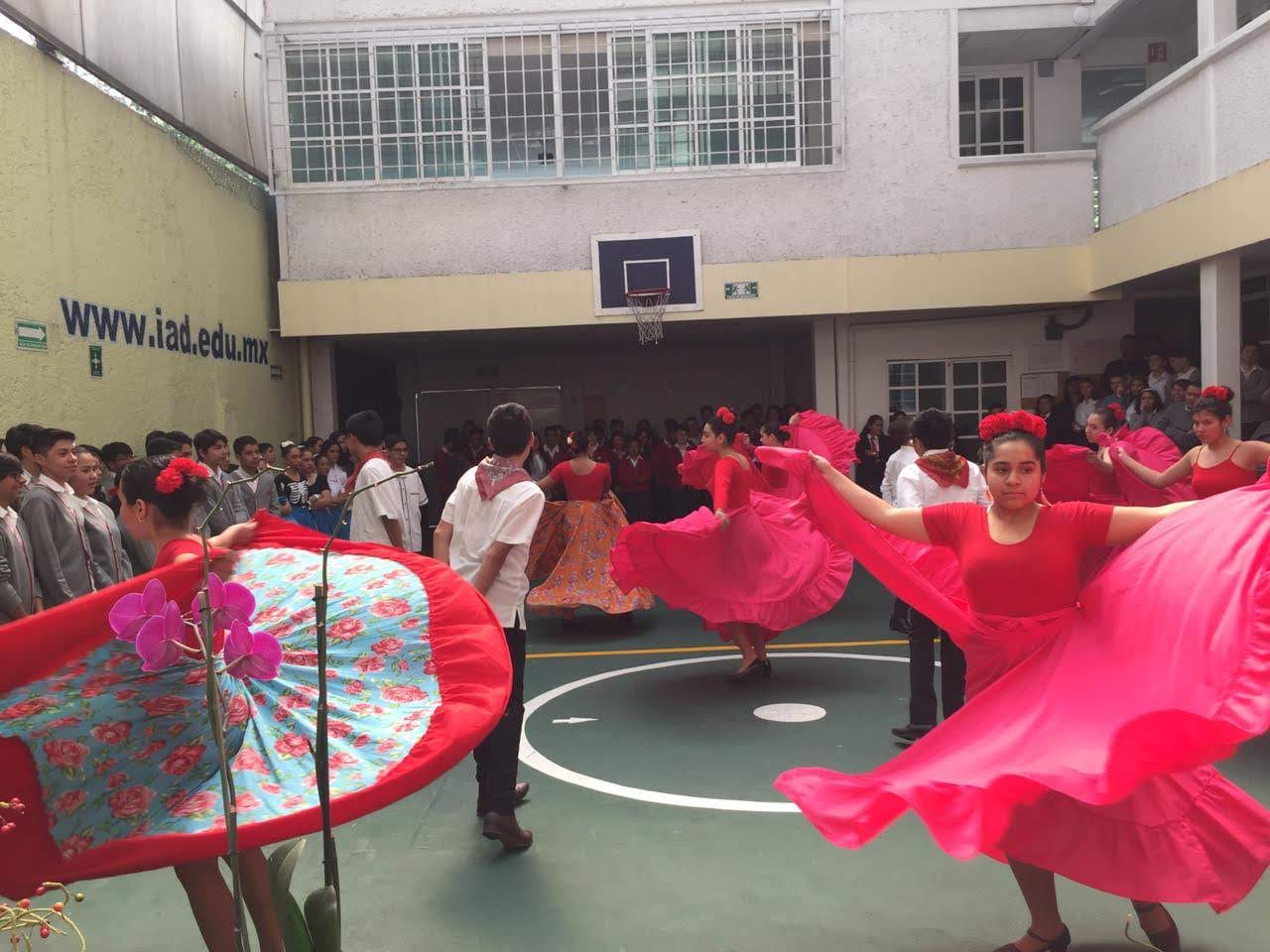 Una alumna extiende su falda roja durante un baile folclórico en el patio, frente a la comunidad escolar