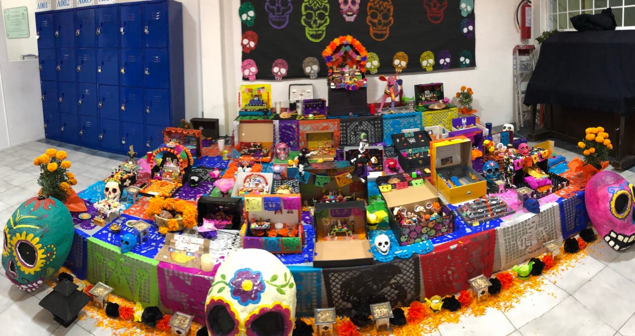 Una gran ofrenda de Día de Muertos con calaveras de colores frente a los casilleros del plantel Parque Victoria