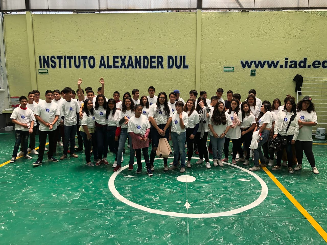 Alumnos de bachillerato con playeras blancas posan juntos en la cancha del plantel