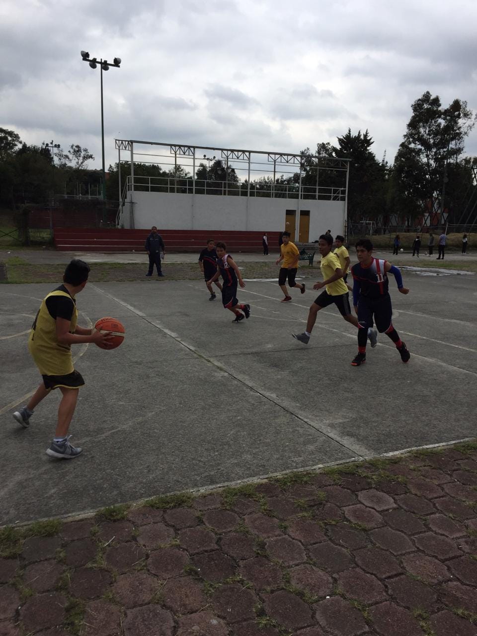 Un alumno bota el balón durante un partido de básquetbol al aire libre