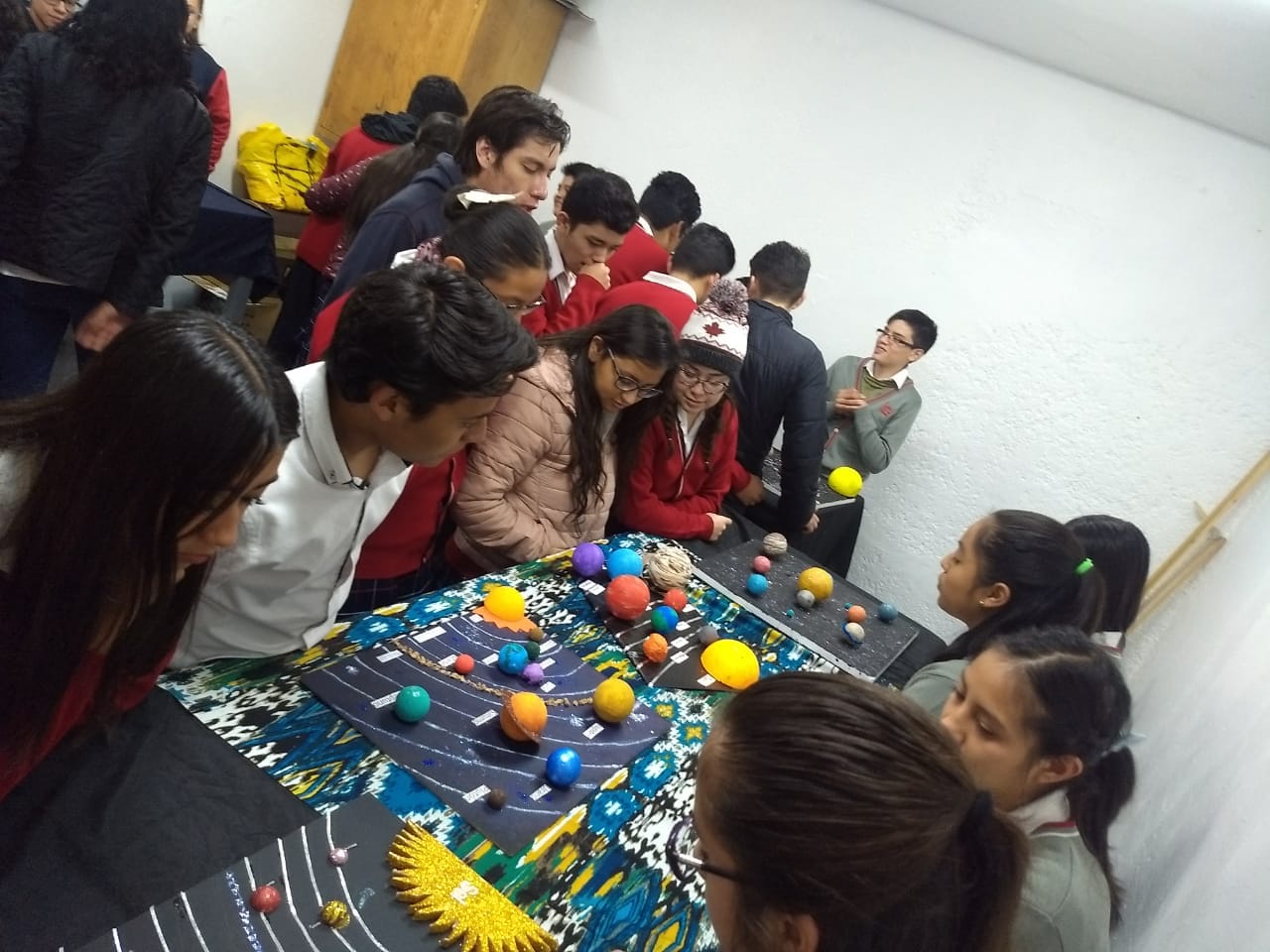 Alumnos de secundaria observan las maquetas del sistema solar que prepararon en clase